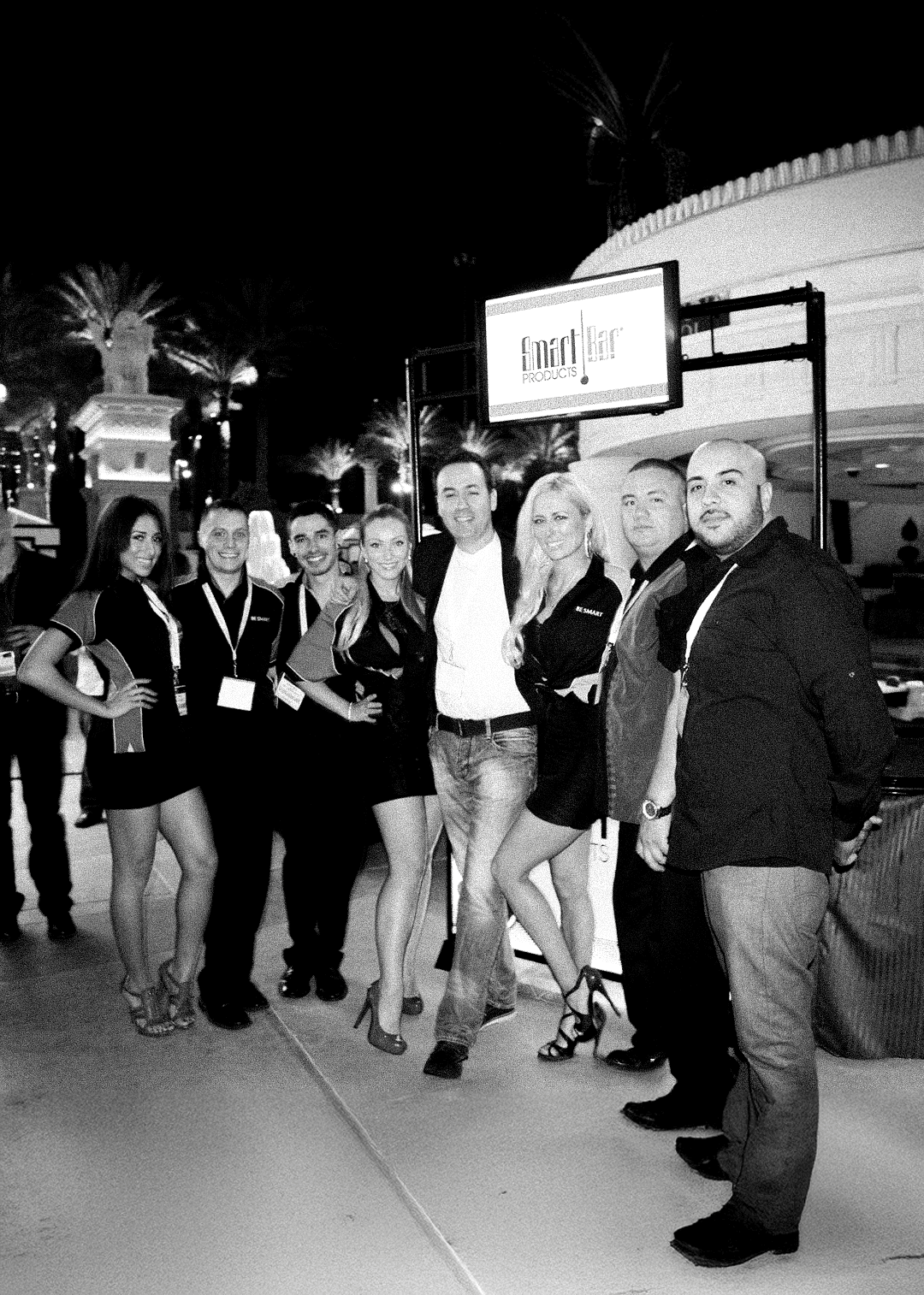 Adam Rozen with a group of colleagues on a street at night, beneath a lit sign